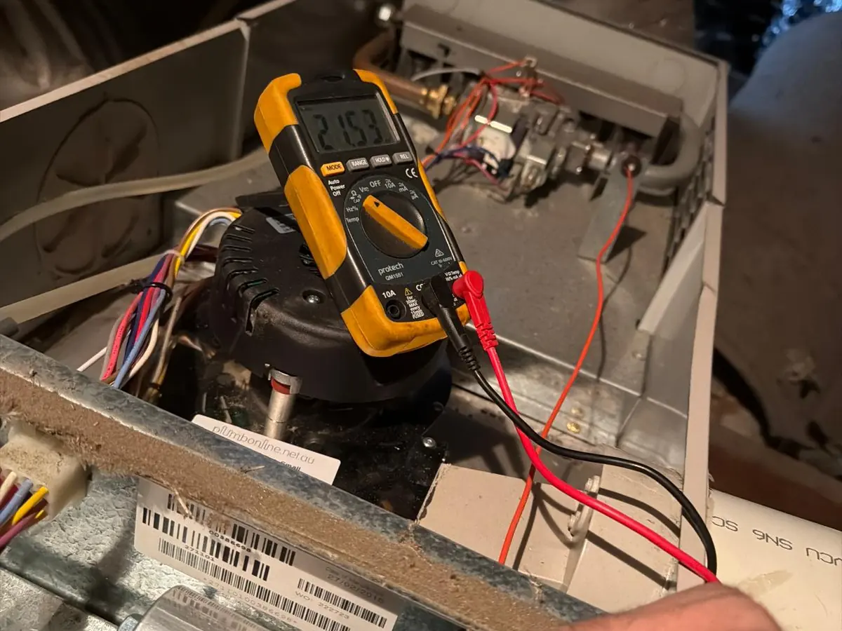Efficient Air and Gasfitting technician testing a ducted heater with a multimeter